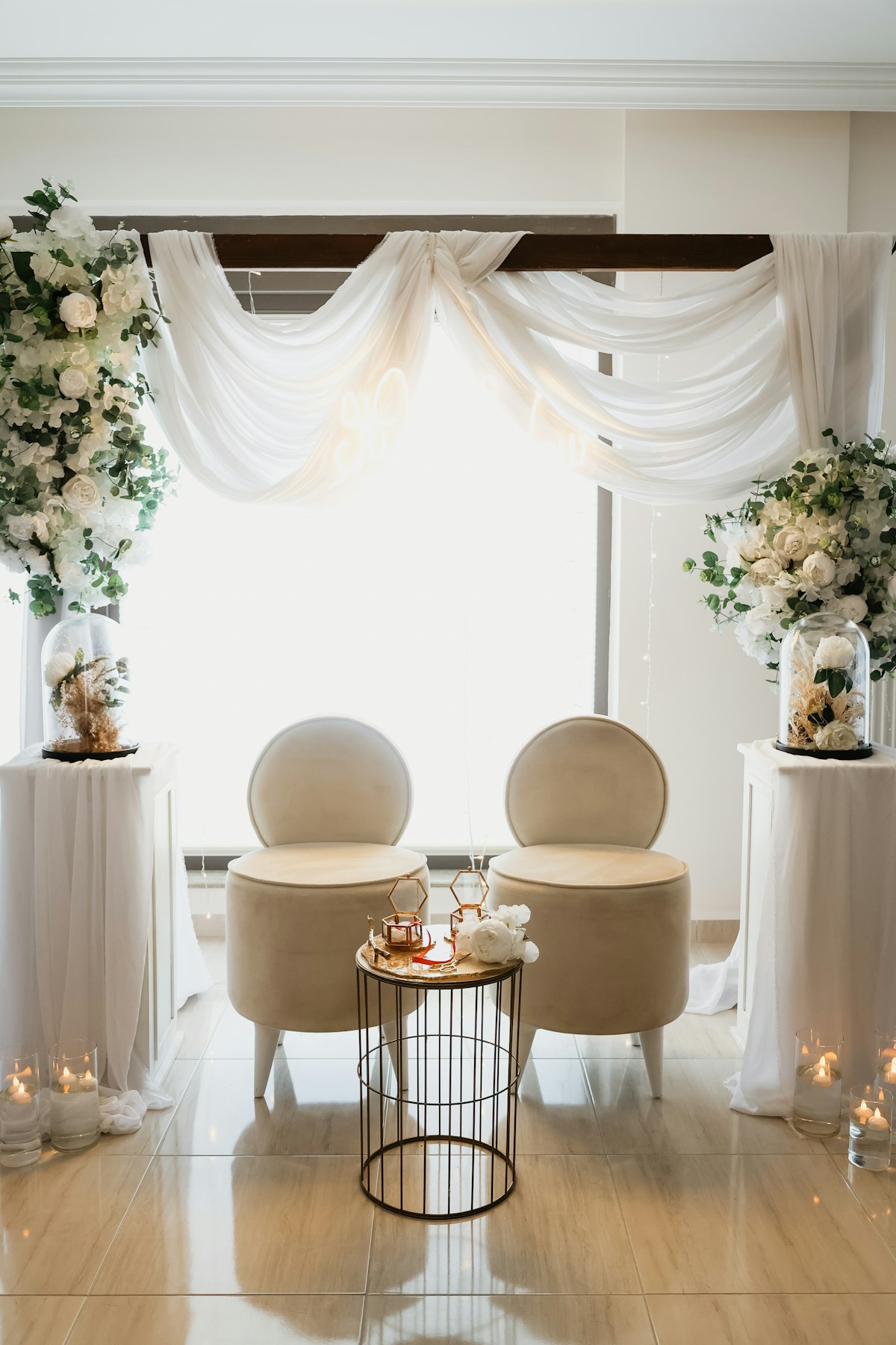 Two decorated chairs beside floral arrangements at a wedding venue